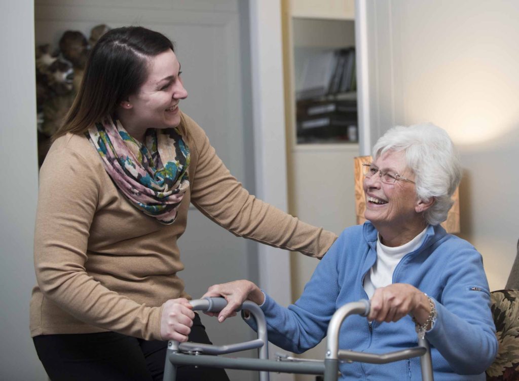 A caregiver helps a senior with Parkinson's to walk.